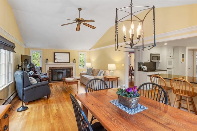 15 Thoreau Rd, Acton, MA 01720 - dining area with vaulted ceiling, light wood-style flooring, ceiling fan, a chandelier, and a fireplace
