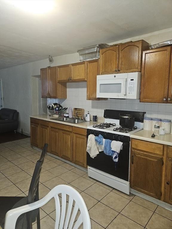 192 Chestnut St, Chelsea, MA 02150 - kitchen featuring range with gas cooktop, white microwave, a sink, and decorative backsplash