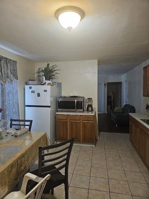 192 Chestnut St, Chelsea, MA 02150 - kitchen with freestanding refrigerator, stainless steel microwave, light countertops, and light tile patterned flooring