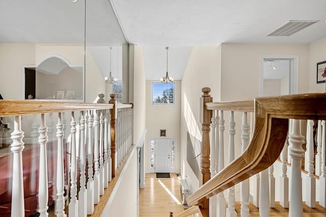 stairway with hardwood / wood-style floors and a chandelier