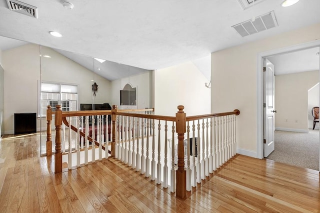 hallway with hardwood / wood-style flooring and vaulted ceiling