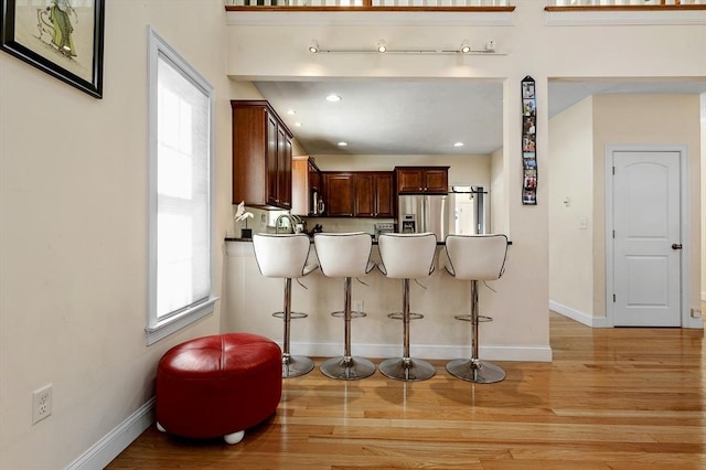 kitchen with stainless steel appliances, kitchen peninsula, a healthy amount of sunlight, and a kitchen bar