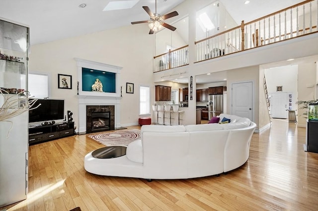 living room featuring ceiling fan, a high end fireplace, light hardwood / wood-style floors, and lofted ceiling