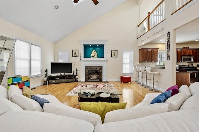 living room featuring ceiling fan, high vaulted ceiling, and light wood-type flooring