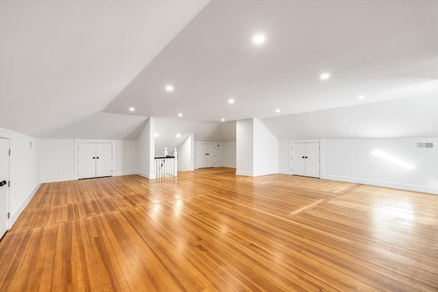 additional living space featuring light hardwood / wood-style floors and lofted ceiling