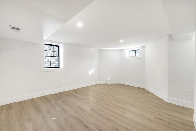 basement with a healthy amount of sunlight and light hardwood / wood-style floors