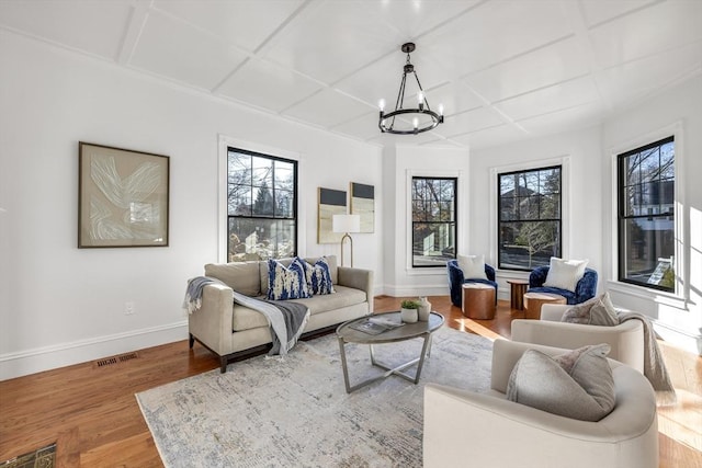 living room featuring a notable chandelier, coffered ceiling, and hardwood / wood-style flooring