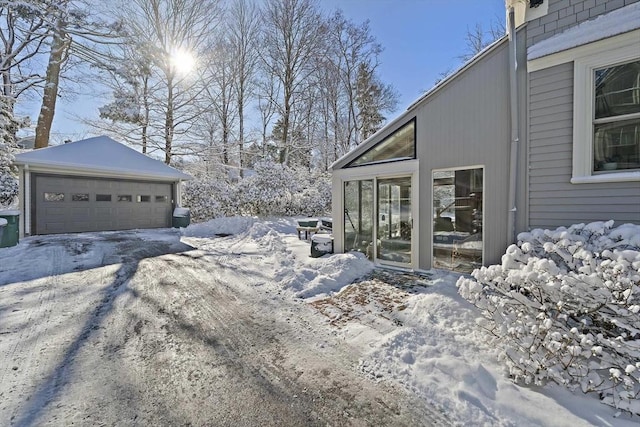 view of snowy exterior with a garage and an outdoor structure