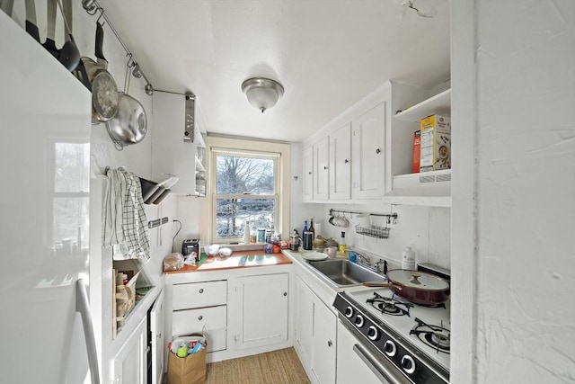 kitchen with white cabinets, white range with gas stovetop, sink, and light hardwood / wood-style flooring