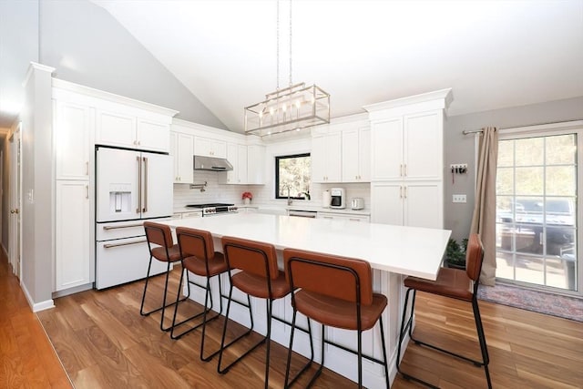 kitchen featuring high end fridge, stainless steel range oven, white cabinetry, a center island, and light hardwood / wood-style flooring