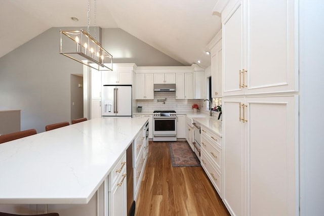 kitchen featuring a breakfast bar, vaulted ceiling, high quality appliances, light hardwood / wood-style floors, and white cabinets