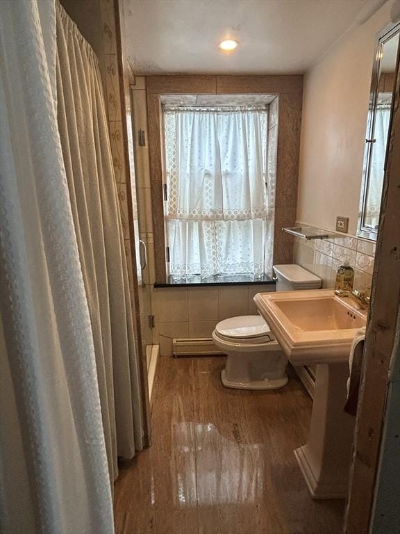 39R Spring St, Boston, MA 02132 - bathroom with a baseboard radiator, tile walls, a shower stall, and wood finished floors