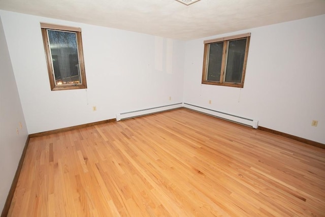 unfurnished room with light wood-type flooring and a baseboard heating unit