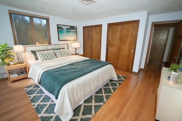 bedroom featuring two closets and light wood-type flooring