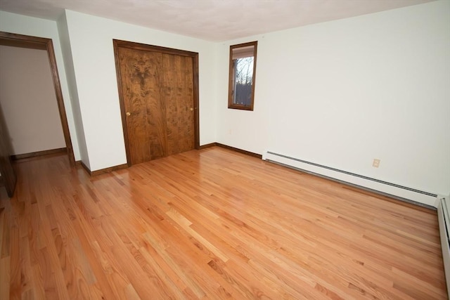 unfurnished bedroom featuring a closet, light hardwood / wood-style flooring, and a baseboard radiator