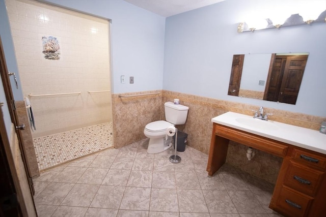 bathroom with sink, tile patterned flooring, toilet, tiled shower, and tile walls