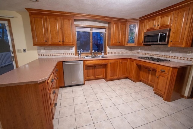 kitchen featuring backsplash, sink, kitchen peninsula, and stainless steel appliances