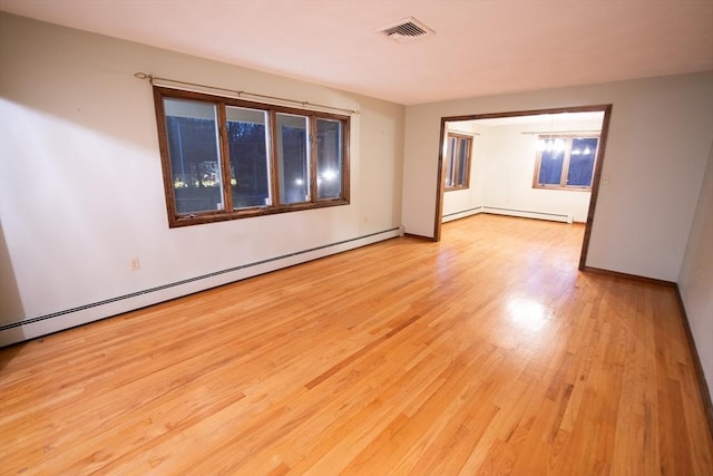 spare room featuring an inviting chandelier, a baseboard radiator, and light hardwood / wood-style flooring