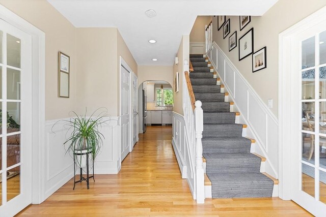 38 Thoreau Cir, Beverly, MA 01915 - foyer entrance featuring arched walkways, a decorative wall, light wood-style floors, stairway, and wainscoting