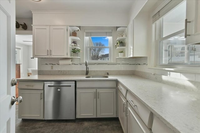 kitchen with sink, white cabinetry, tasteful backsplash, stainless steel dishwasher, and light stone countertops