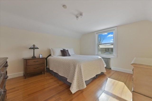 bedroom with vaulted ceiling, radiator, and light hardwood / wood-style floors