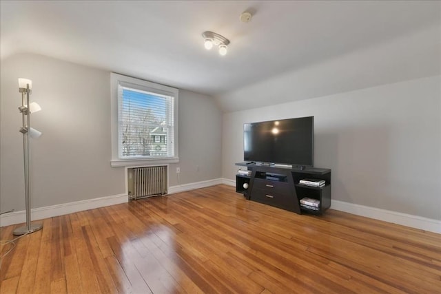 living room featuring hardwood / wood-style flooring, radiator heating unit, and vaulted ceiling