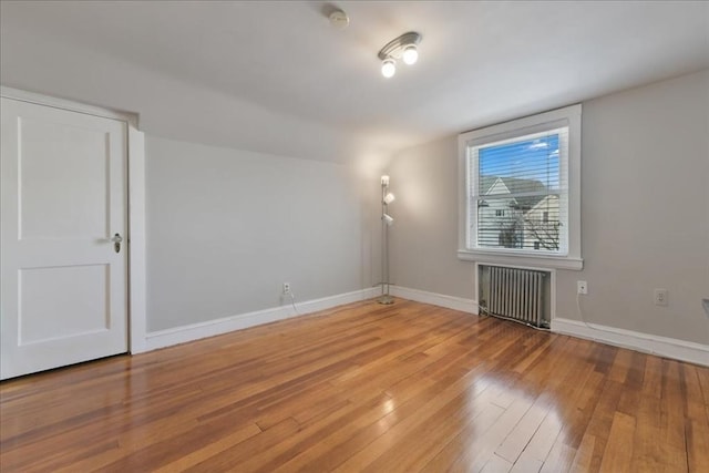 unfurnished room featuring radiator and hardwood / wood-style flooring