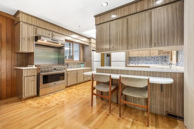 124 Mount Vernon Rd W, Weymouth, MA 02189 - kitchen featuring freestanding refrigerator, high end stove, under cabinet range hood, light countertops, and a peninsula
