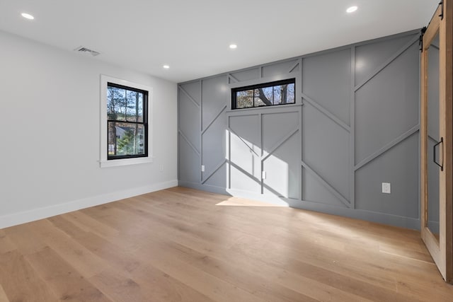 spare room featuring a barn door and light wood-type flooring