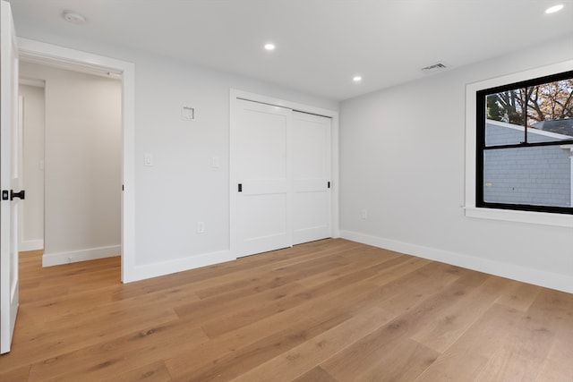 unfurnished bedroom with light wood-type flooring and a closet