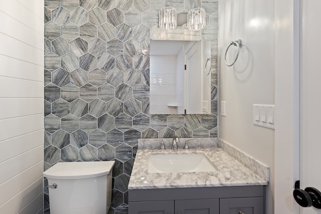 bathroom featuring vanity, toilet, and tile walls