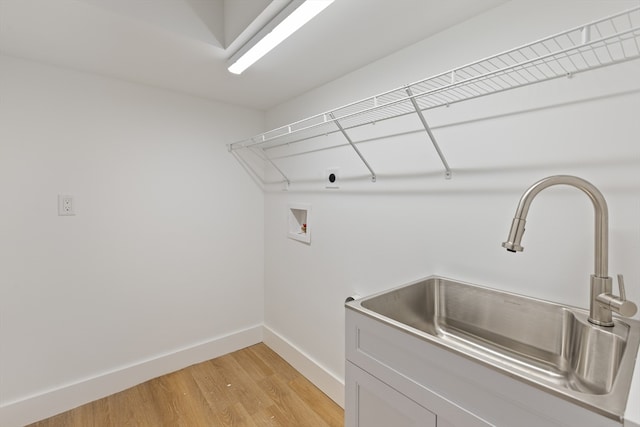 washroom with electric dryer hookup, cabinets, sink, washer hookup, and light hardwood / wood-style floors