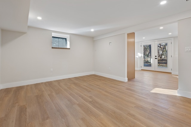 basement featuring light hardwood / wood-style flooring and french doors