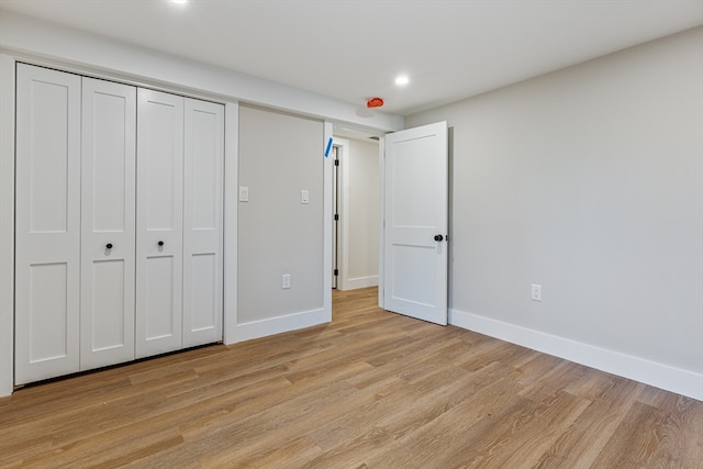 unfurnished bedroom with light wood-type flooring and a closet