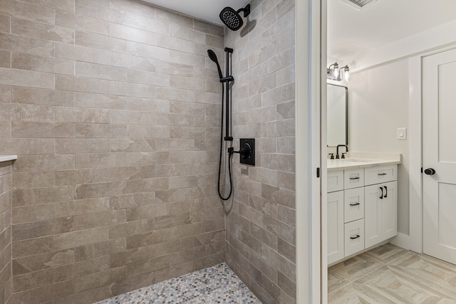 bathroom with a tile shower and vanity