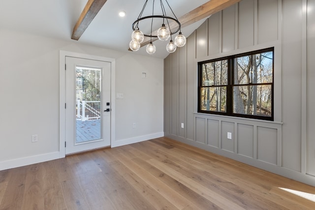 unfurnished dining area featuring beam ceiling, light hardwood / wood-style floors, and a notable chandelier