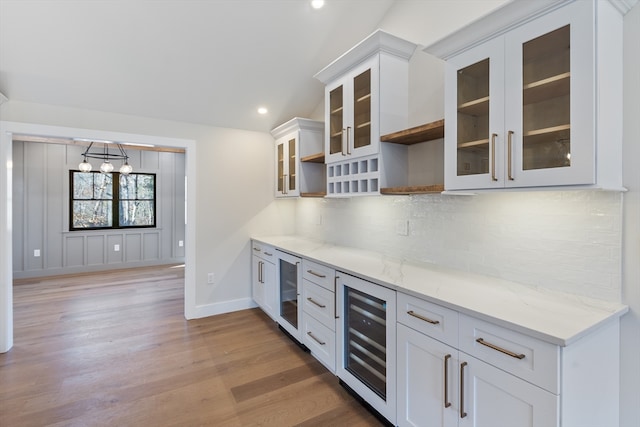 kitchen with light hardwood / wood-style flooring, white cabinetry, beverage cooler, and light stone counters