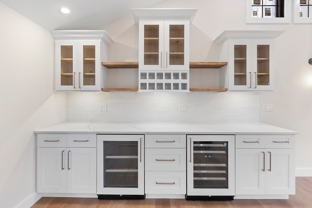 bar with white cabinets, decorative backsplash, light hardwood / wood-style floors, and beverage cooler