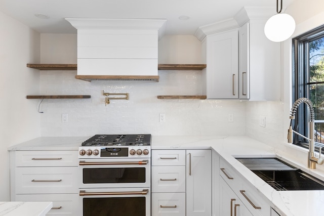 kitchen with white cabinets, decorative light fixtures, stainless steel stove, and tasteful backsplash