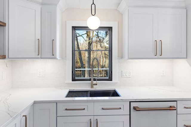 kitchen featuring backsplash, light stone counters, sink, and pendant lighting