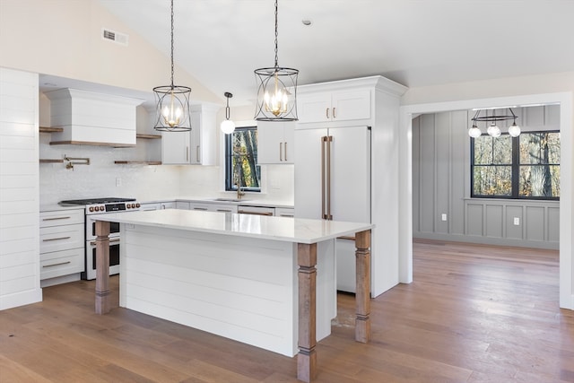 kitchen featuring a wealth of natural light, high quality appliances, white cabinets, and vaulted ceiling