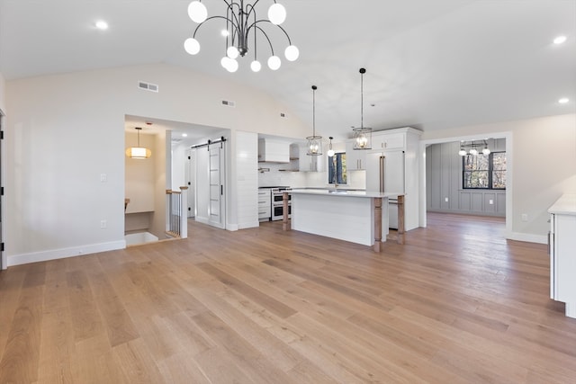 kitchen featuring a barn door, a center island, white cabinets, and hanging light fixtures