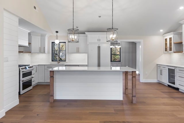 kitchen featuring pendant lighting, high end appliances, white cabinets, wine cooler, and dark hardwood / wood-style flooring