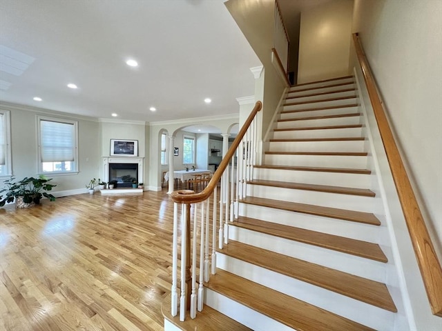 141 Pearl St Unit 141, Newton, MA 02458 - stairs featuring crown molding, arched walkways, recessed lighting, a fireplace with raised hearth, and plenty of natural light