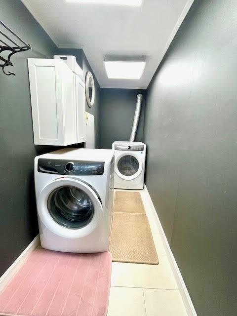 laundry area with tile patterned floors, washer and dryer, and cabinets