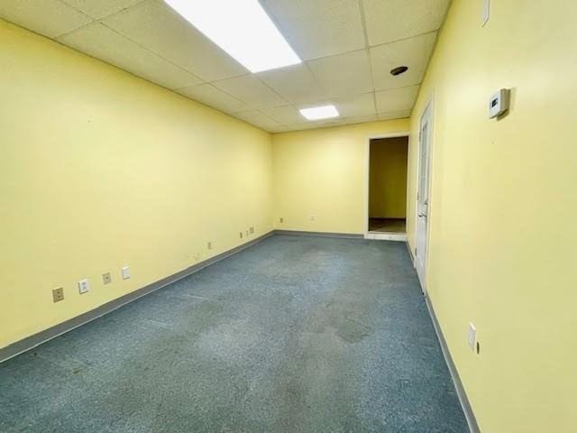 spare room with dark colored carpet and a drop ceiling