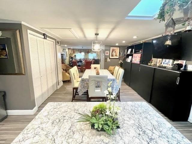 dining room with hardwood / wood-style floors, a skylight, and ornamental molding