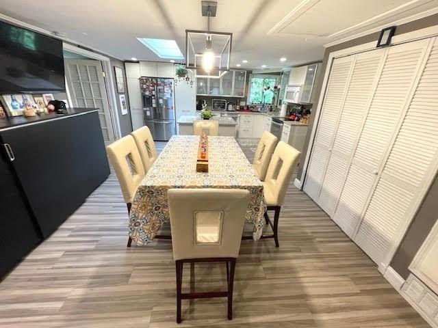 dining area with a skylight and light hardwood / wood-style flooring