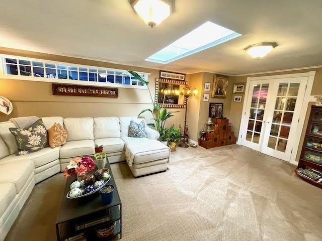 carpeted living room with french doors and a skylight