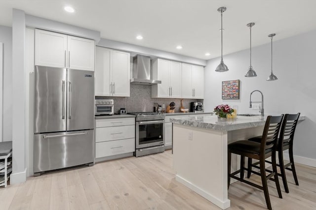 150 W Broadway Unit 203, Boston, MA 02127 - kitchen with stainless steel appliances, wall chimney range hood, light wood-style flooring, tasteful backsplash, and a breakfast bar